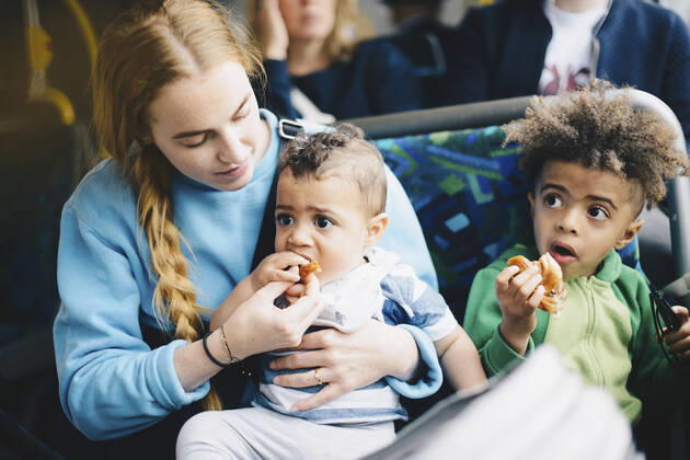 IMAGO Creative: Gesellschaft, Mobilität auf dem Land IMAGO Creative: Stadt-Dichotomien Mother feeding baby boy while sitting with son in bus , model released Copyright: xMaskotx , MA57526