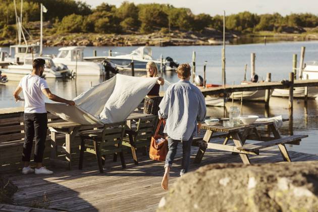 Friends putting cloth on table at jetty on sunny day , model released Copyright: xMaskotx , MA58599