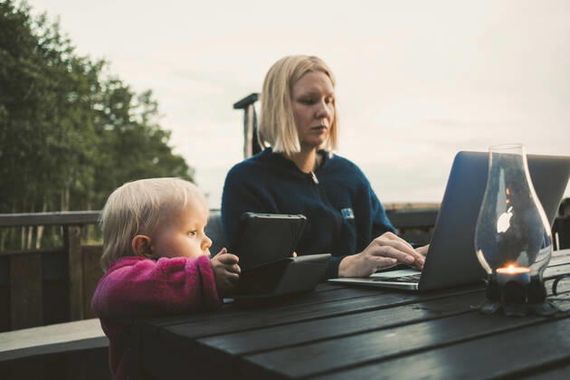 Daughter holding digital tablet while mother using laptop at table against sky , model released, property released Copyright: xMaskotx , MA58791