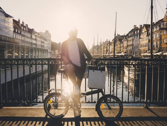 IMAGO Creative, Jahreszeit Sommer, Sommer in der Stadt Full length back lit of man standing with bicycle and shopping bags on footbridge in city , model released Copyright: xMaskotx , MA61429