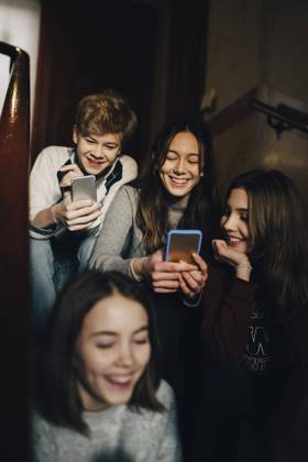 Happy teenage boy with female friends using mobile phone while sitting on steps , model released Copyright: xMaskotx , MA61737