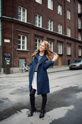 Full length portrait of smiling young woman standing with hand in hair on street against building in city , model released Copyright: xMaskotx , MA62129