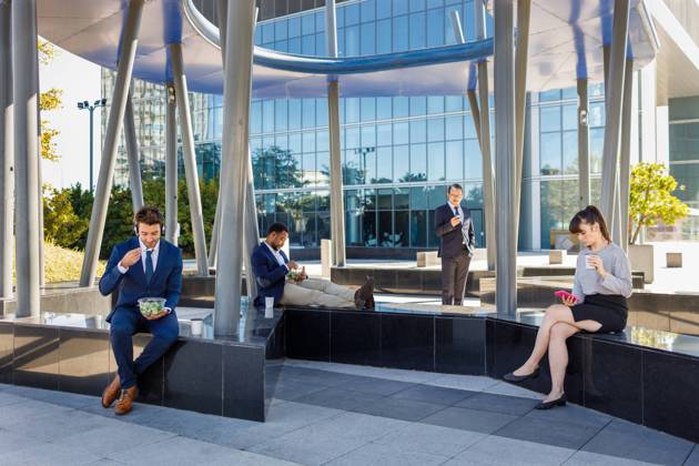 Group of young multiracial coworkers in classy outfits sitting on bench near modern business center and having lunch, Model released Copyright: xIgnacioxFerrandizx MR