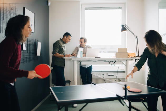Female professionals playing table tennis while male colleagues using laptop at creative office , model released, property released Copyright: xMaskotx , MA63798