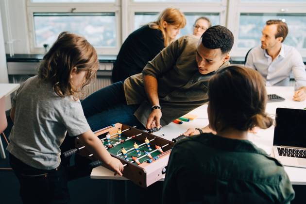 High angle view of boy playing foosball with businessman on desk amidst colleagues at creative office , model released, property released Copyright: xMaskotx , MA63819