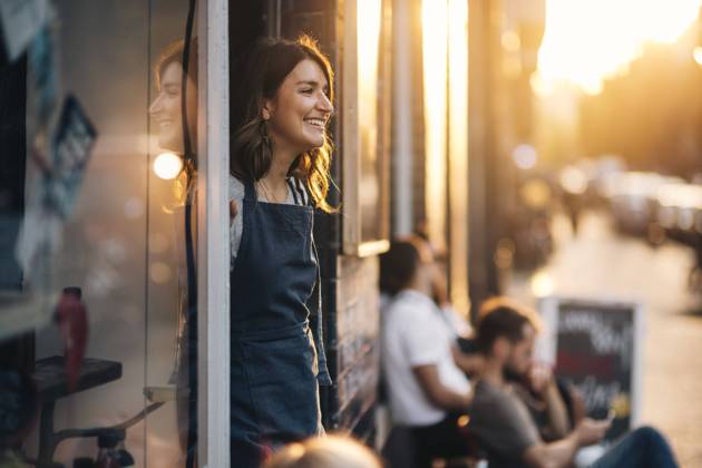 IMAGO Creative, Jahreszeit Sommer, Sommer in der Stadt IMAGO Creative, Frühling, Start der Straßencafe-Saison Smiling female owner looking away while standing at entrance of deli , model released, property released Copyright: xMaskotx , MA67638