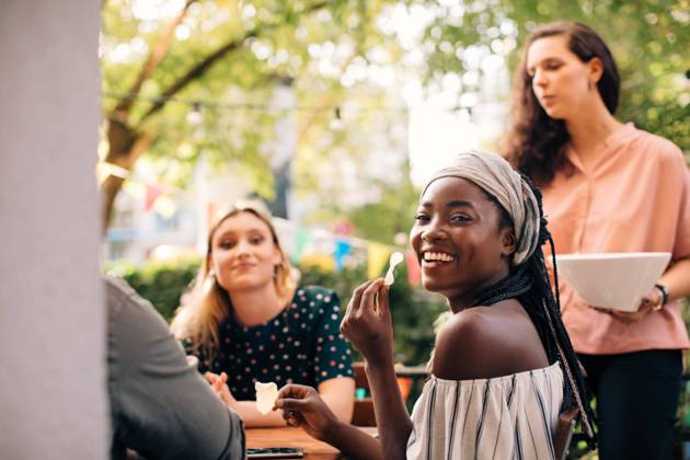 Portrait of smiling young woman eating snacks with friends in balcony , model released, property released Copyright: xMaskotx , MA68095