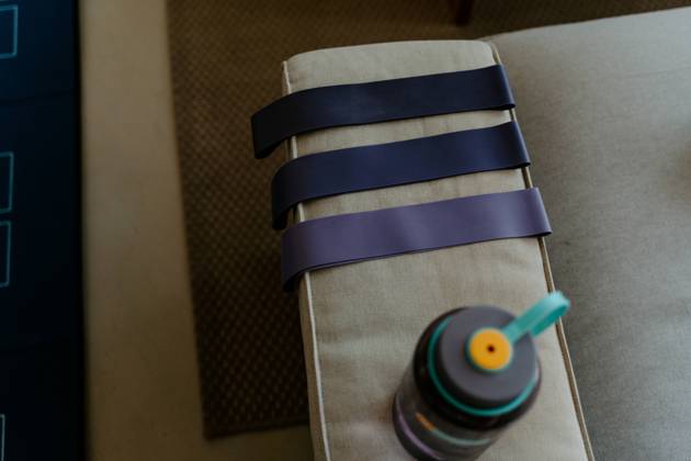 High angle collection of elastic bands of different resistance levels placed on cozy couch arm near water bottle before exercising Copyright: xJakexJakabx Model Released