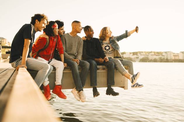 IMAGO Creative, Jahreszeit Sommer, Sommer in der Stadt Happy male friends taking selfie while sitting side by side on pier by river , model released Copyright: xMaskotx , MA69364