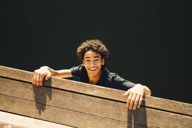 IMAGO Creative, Jahreszeit Sommer, Sommer in der Stadt High angle portrait of cheerful teenage boy hanging from pier against river , model released Copyright: xMaskotx , MA69374