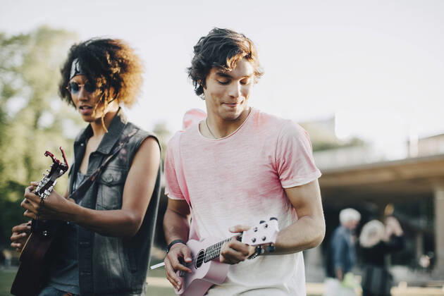Happy young men playing ukulele at music concert in summer , model released Copyright: xMaskotx , MA69817