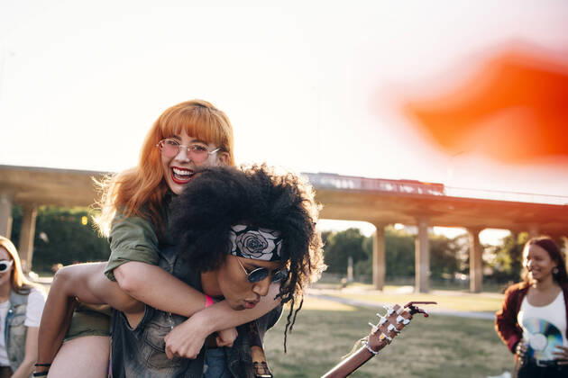 Young man piggybacking happy friend while enjoying in music festival , model released Copyright: xMaskotx , MA69929