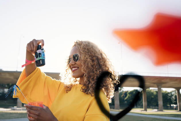 Smiling young woman photographing with camera against sky at event on sunny day , model released Copyright: xMaskotx , MA69950