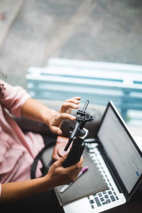Midsection of young female influencer using mobile phone on tripod for vlogging at creative office , model released, property released Copyright: xMaskotx , MA70062