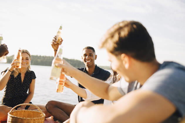 IMAGO Creative: Landleben - Essen Friends enjoying drinks while sitting on jetty against sky in summer , model released Copyright: xMaskotx , MA70447