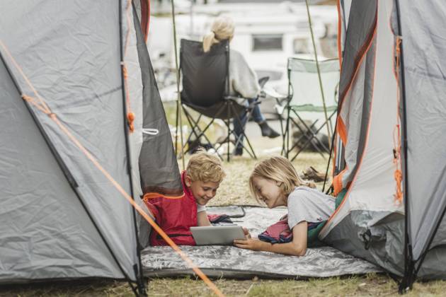 IMAGO Creative, Jahreszeit Sommer, Sommerferien Smiling sister showing digital tablet to brother in tent at campsite , model released, property released Copyright: xMaskotx , MA74513