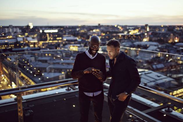 IMAGO Creative, Jahreszeit Sommer, Sommer in der Stadt Smiling businessman showing smart phone to coworker on terrace after office work in city , model released, property released Copyright: xMaskotx , MA74800