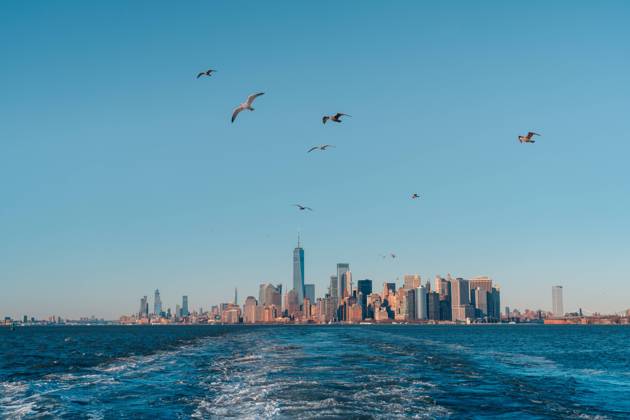 View from floating in water boat of Manhattan skyline with birds flying against blue cloudless sky, Model released Copyright: xJavierxMartinezx MR