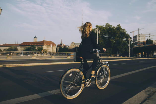 Rare view of female executive riding bicycle on road in city against sky , model released Copyright: xMaskotx , MA77503
