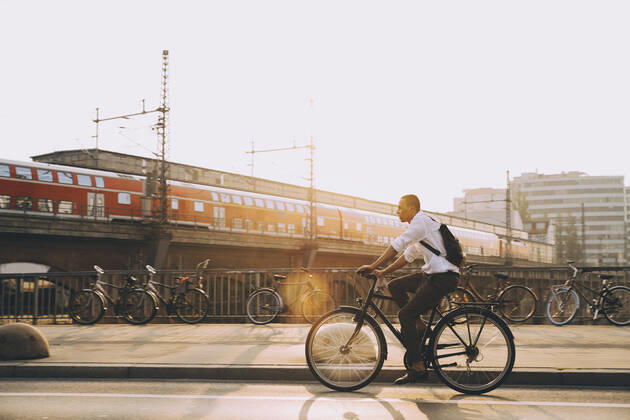 IMAGO Creative: Corporate: Klimaschutz, Digitalisierung und Urbanisierung Full length of businessman with backpack riding bicycle on road in city against sky , model released Copyright: xMaskotx , MA77508