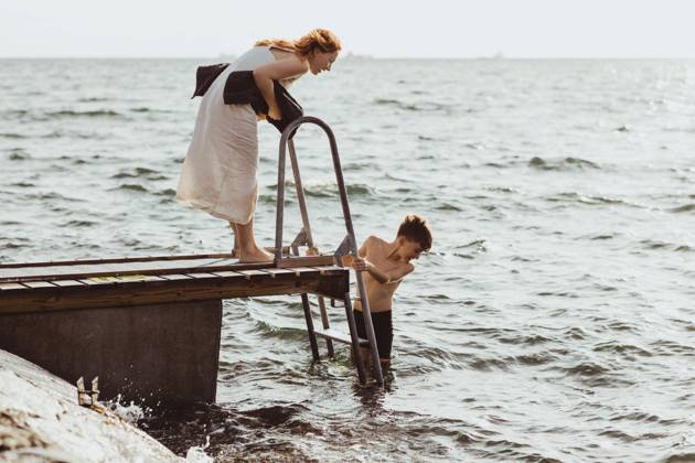 IMAGO Creative, Jahreszeit Sommer, Sommerferien Side view of woman guiding while son moving down on ladder in sea Sweden, Gothenburg, model released Copyright: xMaskotx , MA78859