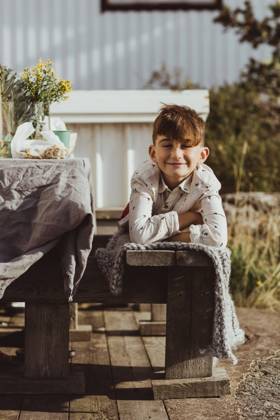 IMAGO Creative, Jahreszeit Sommer, Sommerferien Portrait of smiling boy lying on front over wooden seat Sweden, Gothenburg, model released, property released Copyright: xMaskotx , MA78879