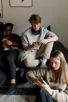Teenage girls and boy using mobile phone while sitting in living room Sweden, Stockholm, model released, property released Copyright: xMaskotx , MA78974