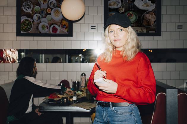 Portrait of female waitress with note pad standing against table in restaurant Sweden, Stockholm, model released, property released Copyright: xMaskotx , MA79654