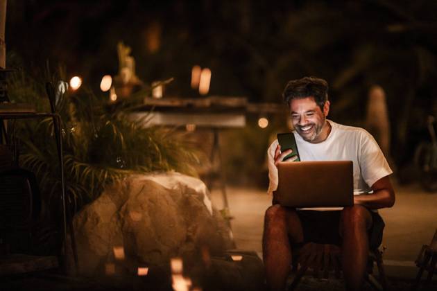 Happy man using phone and laptop at night USA, California, model released Copyright: xMaskotx , MA80902