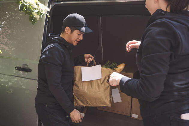Delivery man talking to female colleague while holding package near truck Sweden, Stockholm, model released Copyright: xMaskotx , MA81134