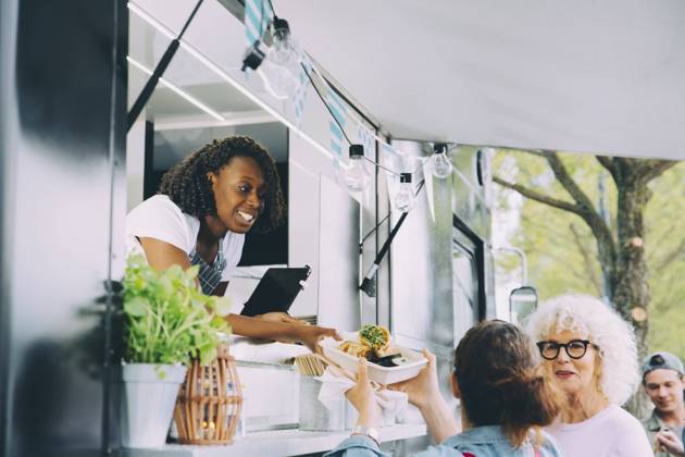 Female owner giving indian food to smiling customers in city Sweden, Stockholm, model released, property released Copyright: xMaskotx , MA81597