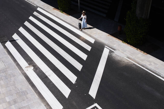Top view of young woman with baggage crossing a street at the airport model released Symbolfoto IGGF01340