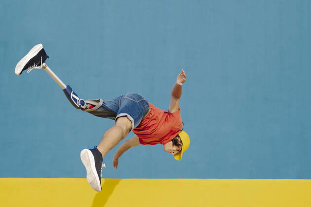 Man with artificial limb and foot jumping against multi colored wall model released Symbolfoto JCZF00271