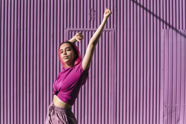 Young woman with dyed red hair dancing in front of purple wall in the city model released Symbolfoto TCEF00999