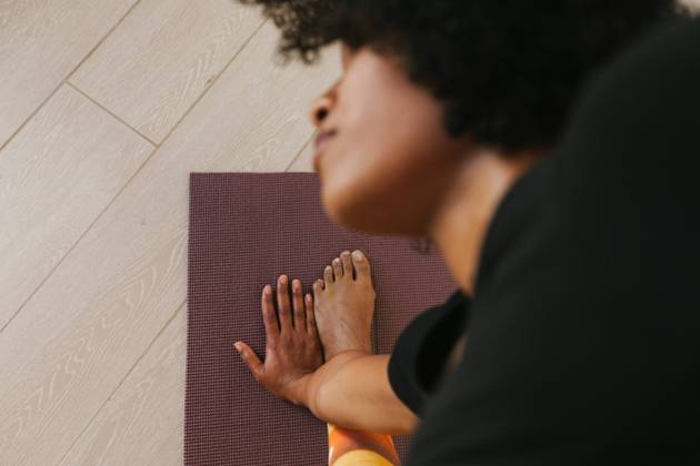 From above close-up view of African American attractive young woman performing yoga pose with closed eyes on a mat at home, Model released Copyright: xTadeuxDreyerx MR