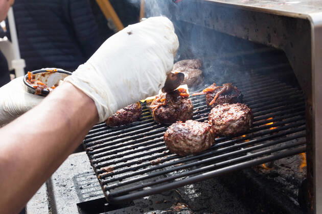 Beef burgers being grilled on food stall grill. Chef making beef burgers outdoor on open kitchen international food festival event. Street food ready to serve on a food stall.burger, grill, hamburger, street food, food, beef, stall, street, fast, meat, snack, outdoors, cuisine, seller, vendor, catering, lunch, meal, delicious, restaurant, junk food, sauce, outdoor, urban, event, making, chef, decorate, to go, take out, cart, plate, dressing, healthy, city, open kitchen, cheese, bacon, specialty, topping, pork, oven, stove, glove, fest, 