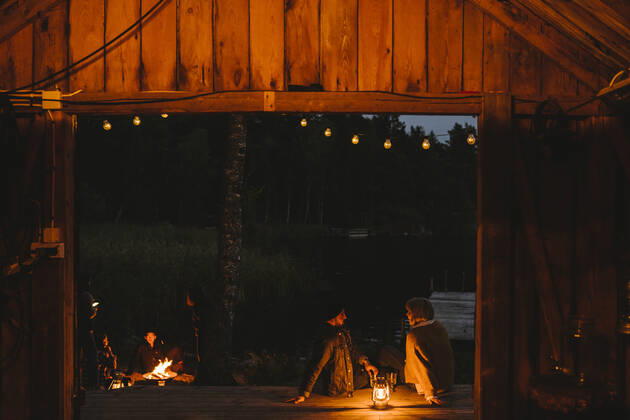 Couple talking while friends sitting by fire pit during sunset Sweden, Stockholm, model released, property released Copyright: xMaskotx , MA83218