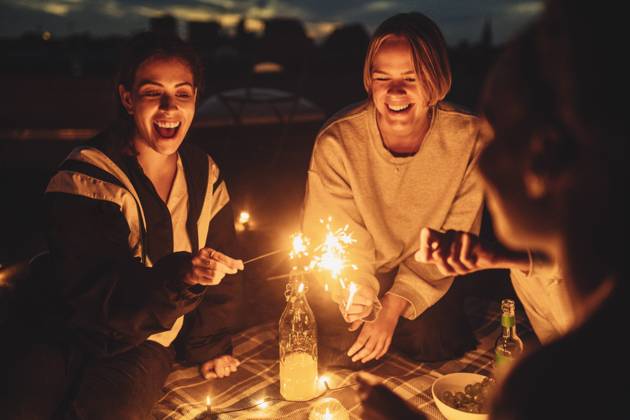 IMAGO Kreativ: Urbane Kultur - Sommer auf den Dächern Cheerful female with friends igniting sprinkler on building rooftop at night Germany, Berlin, model released, property released Copyright: xMaskotx , MA83575