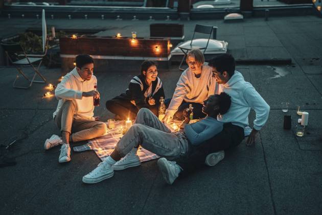 IMAGO Creative: Jahreszeit Frühling, Picknick High angle view of male and female friends talking on building terrace during sunset Germany, Berlin, model released, property released Copyright: xMaskotx , MA83578