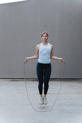 Young woman skipping rope while standing against wall model released Symbolfoto FMOF01261