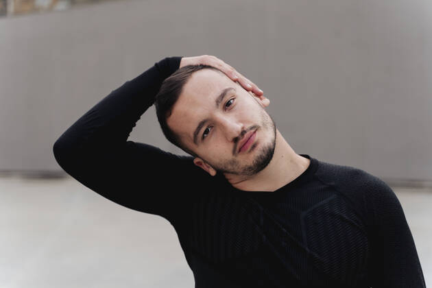 Man stretching head while standing against wall model released Symbolfoto FMOF01278