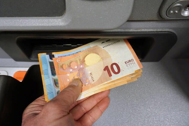 Cash supply from a cash dispenser A person withdraws a large amount of cash from a cash dispenser in 50,20 and 10 Euro notes