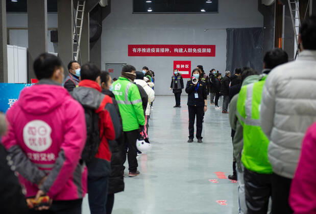 (210102) -- BEIJING, Jan. 2, 2021 -- A staff member (C) leads the way for people waiting for the COVID-19 vaccination at a temporary vaccination site in Beijing, capital of China, Jan. 2, 2021. Beijing started administering COVID-19 vaccines among specific groups of people with higher infection risks. Nine groups of people aged 18 to 59 will receive the vaccine before the Spring Festival of 2021, which falls on Feb. 12. These include frontline customs inspectors of imported cold-chain goods and personnel working in the overseas and domestic transportation sector. ) CHINA-BEIJING-COVID-19-VACCINATION (CN) ChenxZhonghao 