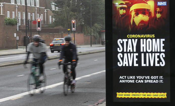 (210110) -- LONDON, Jan. 10, 2021 -- People cycle past an advertising board reading Stay Home Save Lives in London, Britain, Jan. 10, 2021. The coronavirus-related deaths in Britain surpassed 80,000 on Saturday with another 1,035 reported in the country. ) BRITAIN-LONDON-COVID-19-CASES HanxYan 