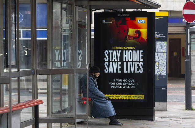 (210110) -- LONDON, Jan. 10, 2021 -- A person wearing a face mask sits next to an advertising board reading Stay Home Save Lives at a bus stop in London, Britain, Jan. 10, 2021. The coronavirus-related deaths in Britain surpassed 80,000 on Saturday with another 1,035 reported in the country. ) BRITAIN-LONDON-COVID-19-CASES HanxYan 