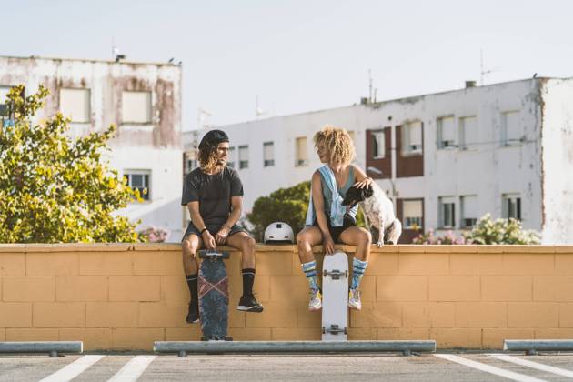 IMAGO Creative, Urban Lifestyle IMAGO Creative, Jahreszeit Sommer, Sommer in der Stadt Friends with skateboard and dog talking while sitting on retaining wall in city model released Symbolfoto DAMF00555