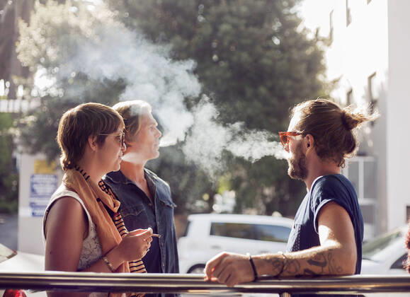 Friends smoking while standing outdoors on sunny day model released Symbolfoto AJOF00383