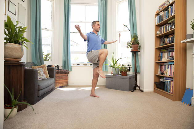 Mature man balancing on leg while standing at home model released Symbolfoto property released PMF01461