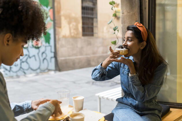Friends eating food while sitting by window at cafe model released Symbolfoto property released VABF03923
