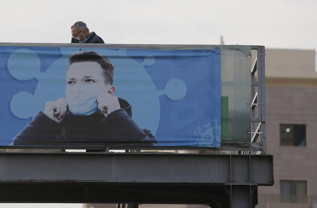 (210111) -- BEIRUT, Jan. 11, 2021 -- A man is seen behind a poster encouraging mask wearing in Beirut, Lebanon, on Jan. 11, 2021. Lebanon s Higher Defense Council declared on Monday a state of emergency between Jan. 14-25 that includes a total lockdown in hope to restrict further spread of COVID-19, Al-Jadeed local TV channel reported. ) LEBANON-BEIRUT-COVID-19-STATE OF EMERGENCY BilalxJawich 